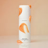 BESPOK cream bottle with orange accents on a beige background